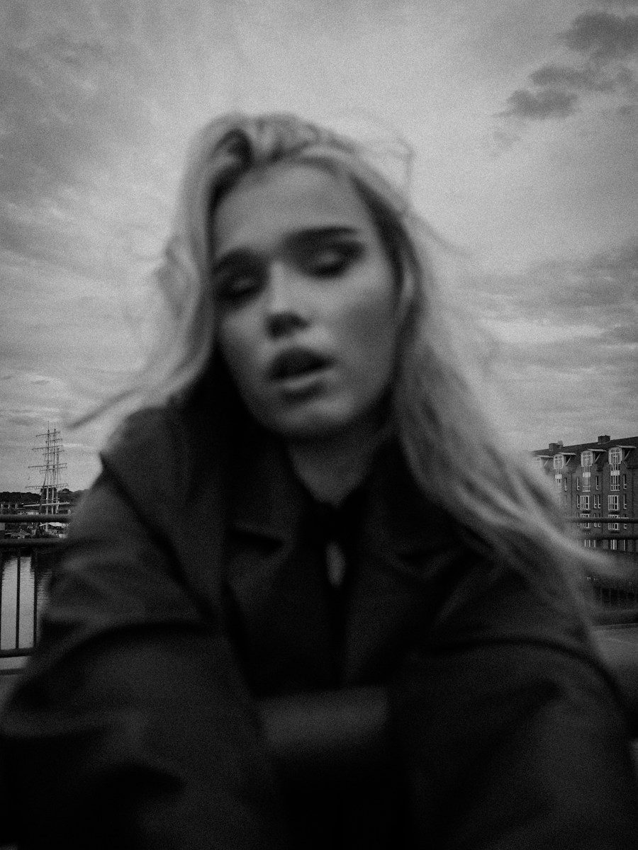 A woman with long hair in a dark coat on a bridge